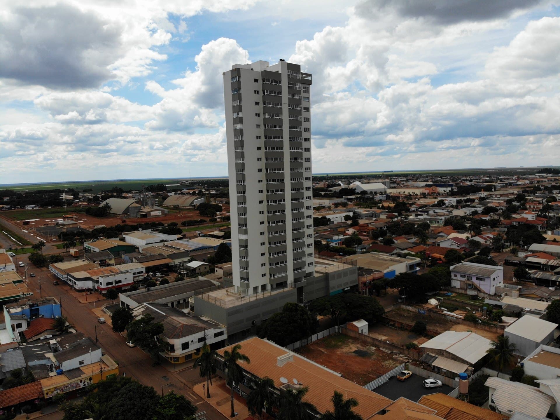 Vista aérea do Edifício São Salvador, a torre mais alta do centro de Campo Novo do Parecis, com a cidade em volta e a lavoura no horizonte