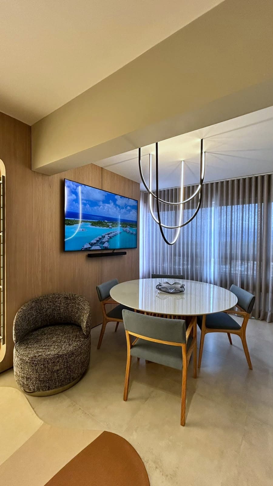 Sala de jantar com mesa redonda, luminária em arco e painel de madeira